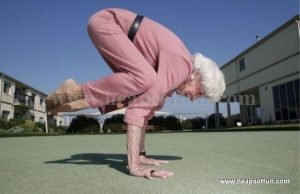 AN image of an elderly woman in her 80's in a pink jumpsuit performing a handstand